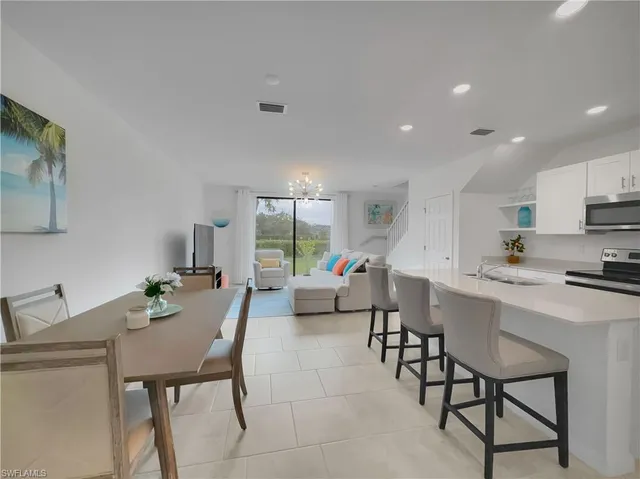 a living room with furniture white walls and kitchen view