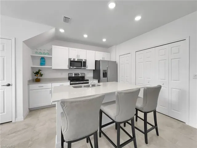 a kitchen with a table chairs refrigerator and microwave
