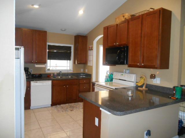 5780 Southeast Colee Avenue Stuart, FL 34997 - Photo 7 of 25 a kitchen with stainless steel appliances granite countertop a sink stove and refrigerator