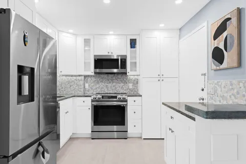 a kitchen with stainless steel appliances granite countertop a refrigerator stove and sink