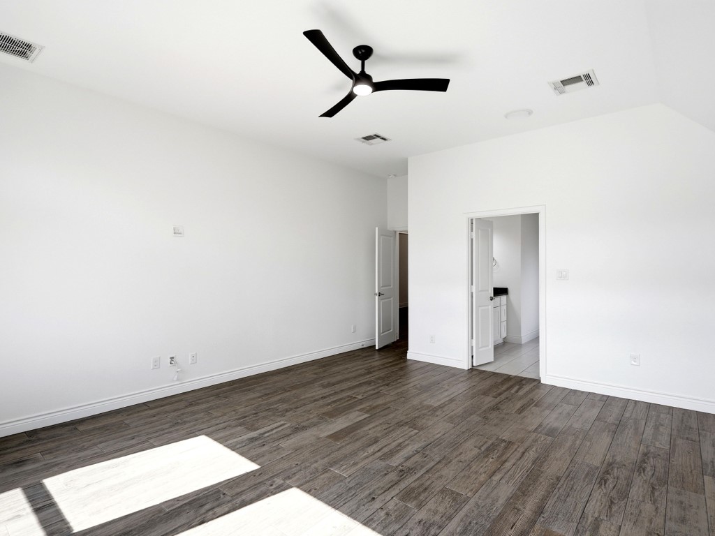 109 Lake Spring Circle Georgetown, TX 78633 - Photo 23 of 38 A spacious primary bedroom features rich wood look tile flooring, high ceilings, and an en-suite bathroom access.