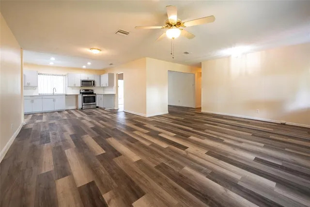 a view of kitchen and empty room with wooden floor