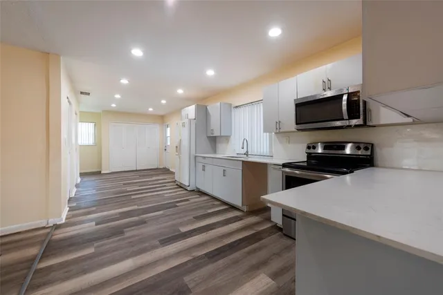 a kitchen with stainless steel appliances kitchen island granite countertop a sink and a stove top oven with wooden floor