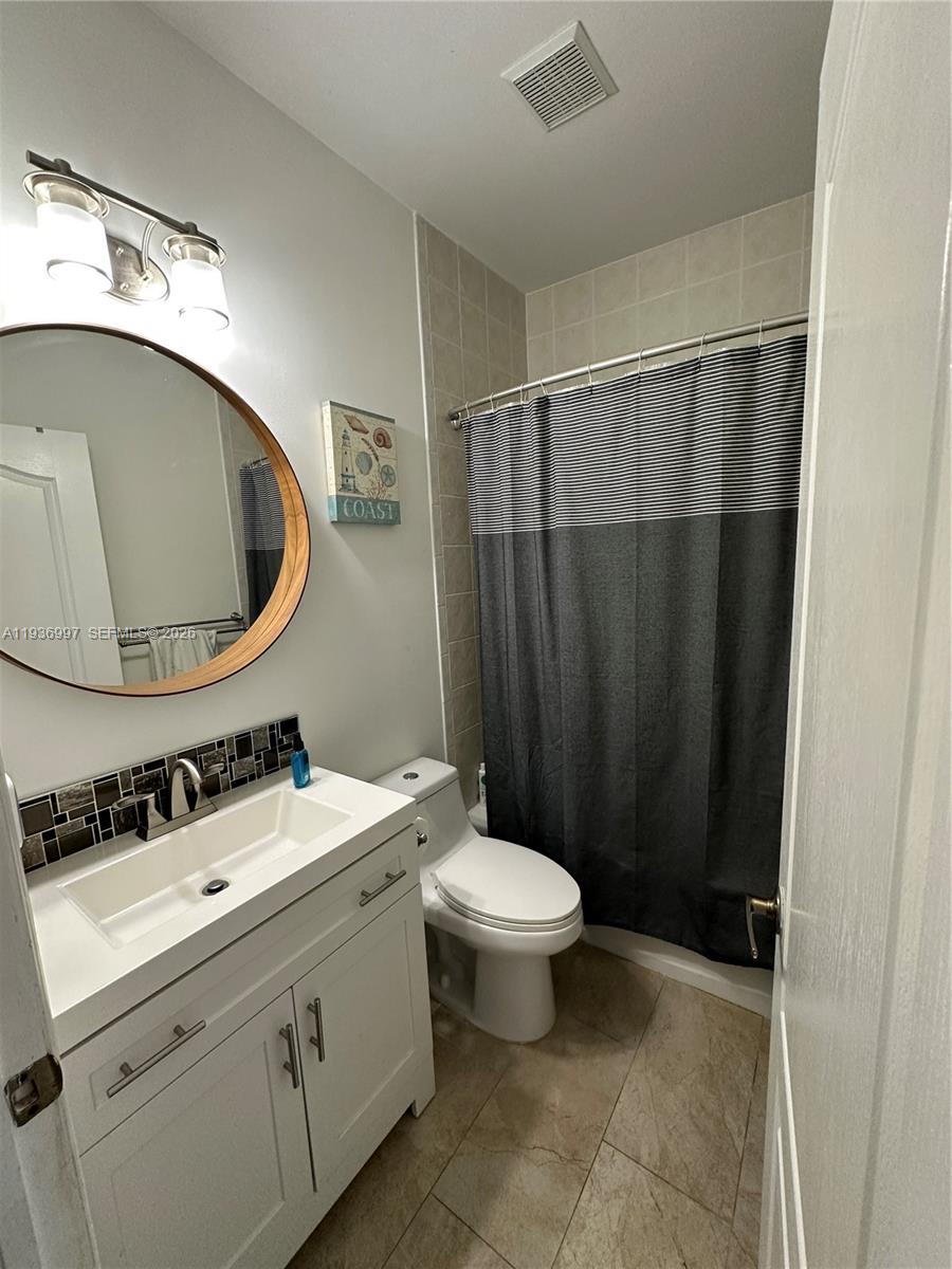 15313 Southwest 31st Terrace, Unit 15313 Miami, FL 33185 - Photo 15 of 21 a bathroom with a sink a toilet and a mirror