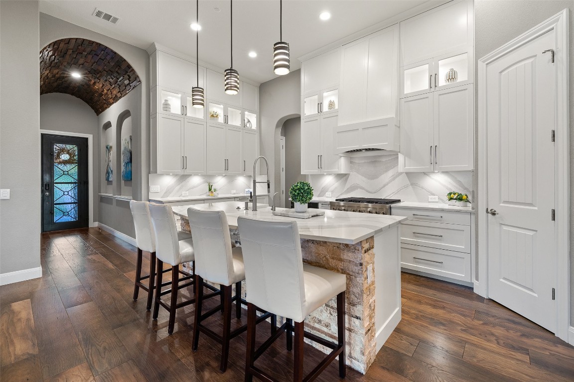a kitchen with stainless steel appliances kitchen island granite countertop a table chairs and white cabinets