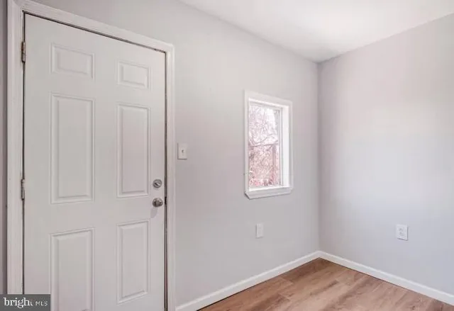 an empty room with wooden floor closet and windows