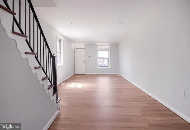 a view of an empty room with wooden floor and stairs
