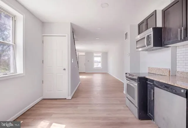 a view of a kitchen with stainless steel appliances wooden floor and a window