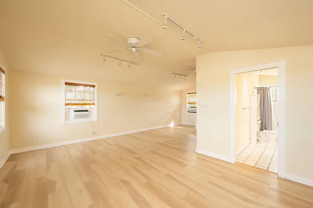 a view of an empty room with wooden floor and a bathroom
