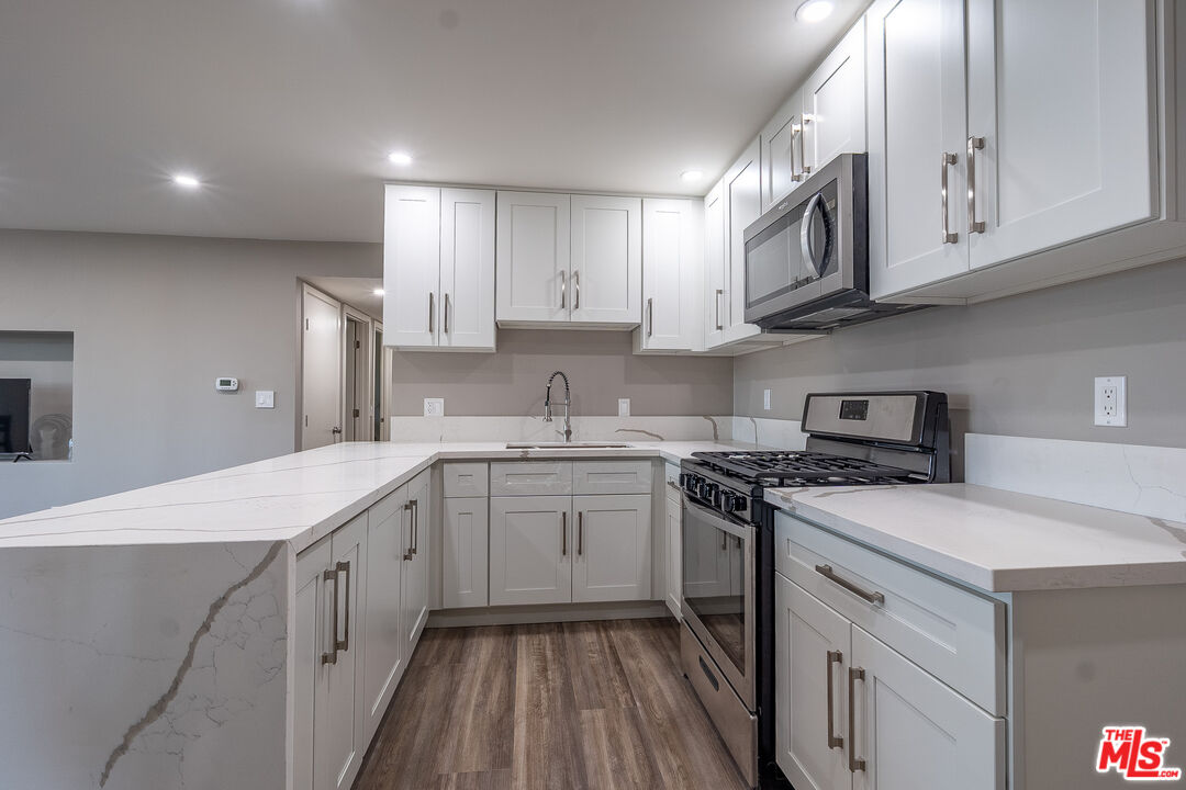 20456 Strathern Street Winnetka, CA 91306 - Photo 30 of 37 a kitchen with stainless steel appliances granite countertop a sink and stove top oven