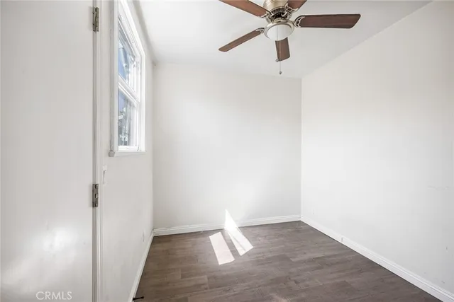 an empty room with wooden floor and ceiling fan