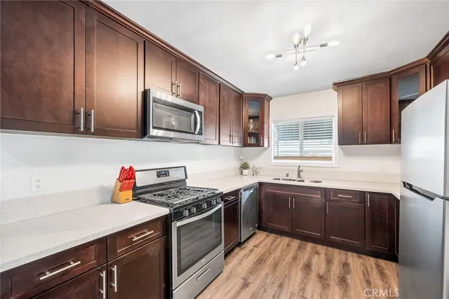 a kitchen with stainless steel appliances granite countertop a refrigerator a sink dishwasher a stove and white countertops with wooden floor