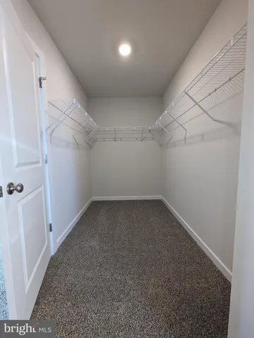 a large kitchen with kitchen island a stove a sink a refrigerator and white cabinets with wooden floor