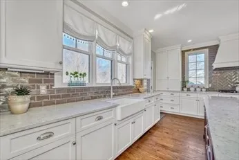 a large white kitchen with stainless steel appliances granite countertop a lot of counter space and a sink