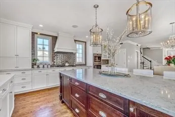 a kitchen with stainless steel appliances granite countertop a sink dishwasher and white cabinets with wooden floor