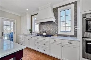a kitchen with granite countertop white cabinets stainless steel appliances a sink and a window