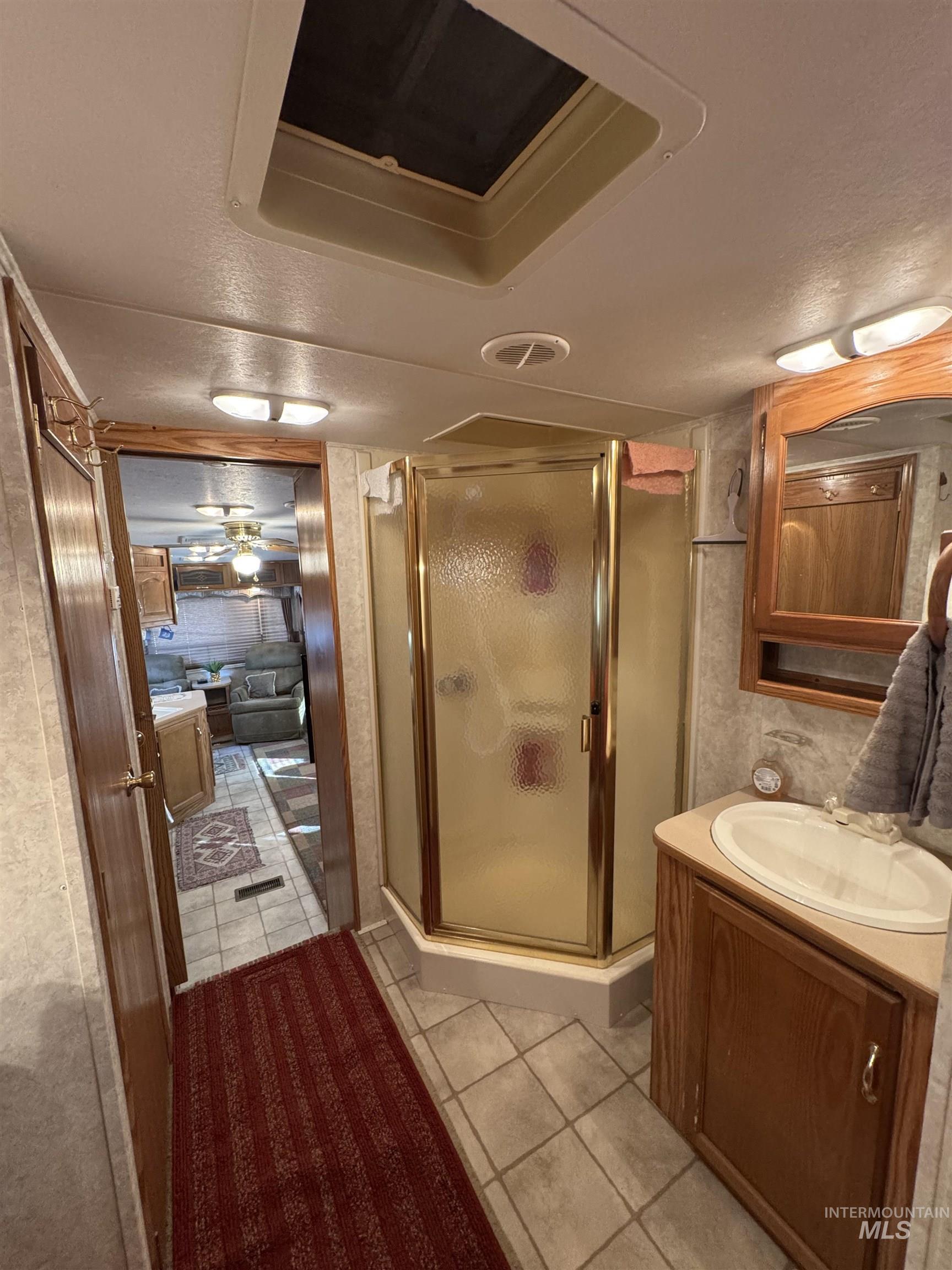 29 B Street Cascade, ID 83611 - Photo 11 of 24 Bathroom featuring a stall shower, light tile patterned flooring, a textured ceiling, vanity, and cooling unit