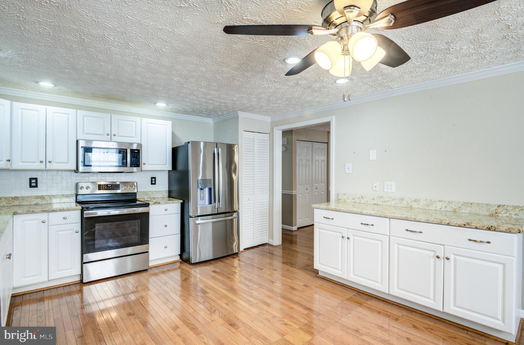 9 Burr Hill Drive Ocean Pines, MD 21811 - Photo 47 of 82 a kitchen with stainless steel appliances granite countertop a refrigerator a stove a sink and white cabinets with wooden floor