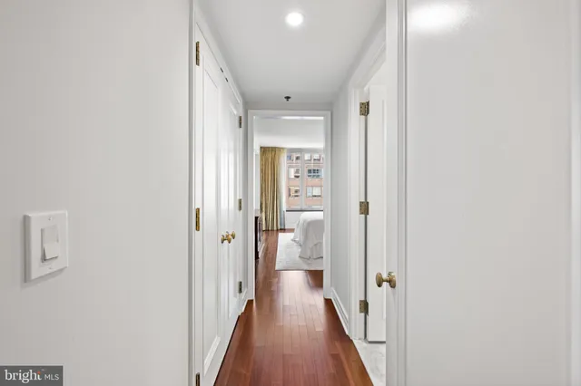 a view of a hallway with wooden floor and a bathroom