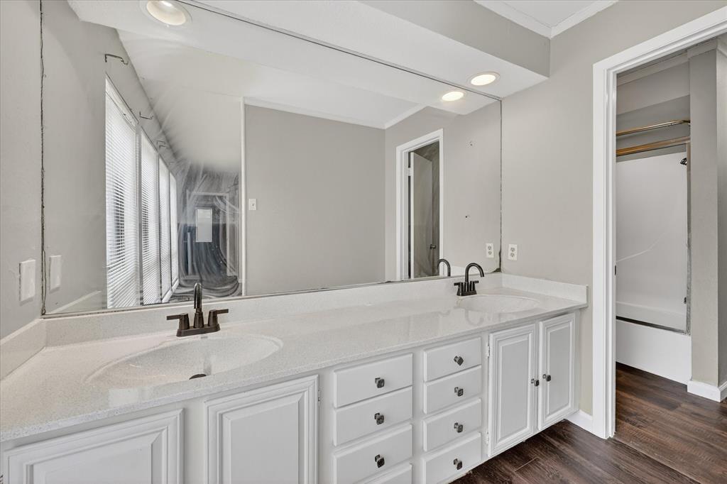 9809 Matchpoint Place Dallas, TX 75243 - Photo 18 of 21 Bathroom featuring a dual vanity with white cabinetry and dark hardware, set against a large wall-mounted mirror