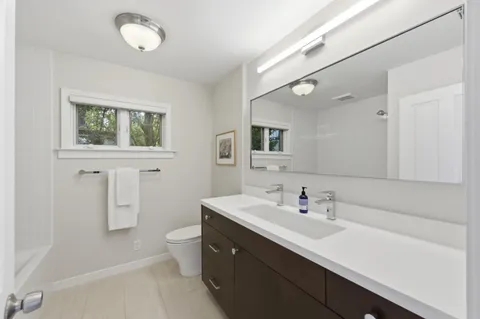 a bathroom with a sink a toilet a light fixture and a mirror