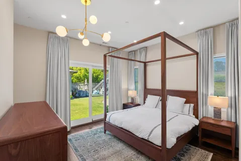 a bedroom with a bed a chandelier and a window