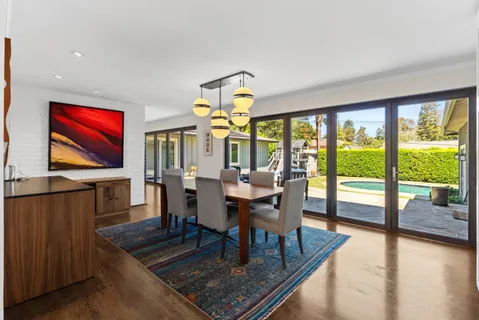 a dining room with furniture a rug and a floor to ceiling window
