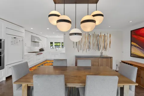 a kitchen with stainless steel appliances granite countertop a stove a sink a dining table and chairs with wooden floor