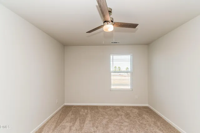 an empty room with closet and a ceiling fan