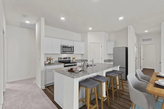 a kitchen with stainless steel appliances a stove a sink a refrigerator a stove a dining table and chairs