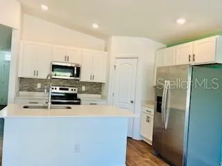 a kitchen with a refrigerator a stove top oven and cabinets