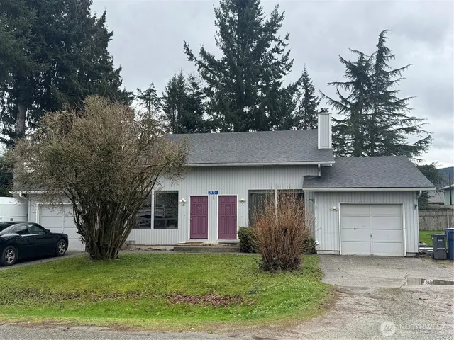 a view of a yard in front of a house with large tree and plants