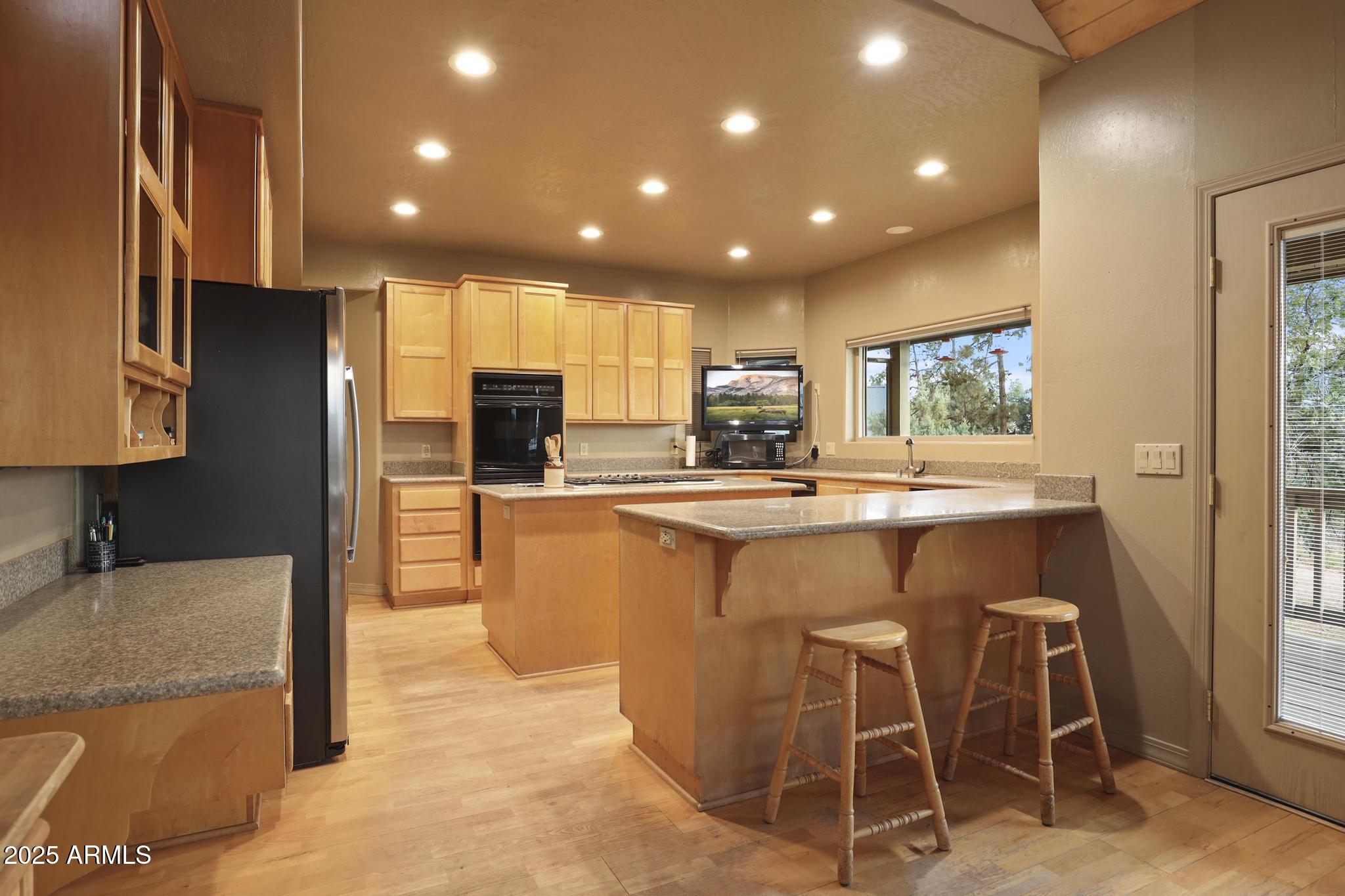 131 West Hunt Ranch Road Pine, AZ 85544 - Photo 12 of 65 a kitchen with kitchen island granite countertop wooden cabinets and a refrigerator