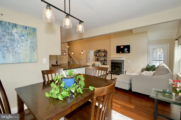 a kitchen with stainless steel appliances granite countertop a refrigerator a sink dishwasher a stove and a dining table with wooden floor