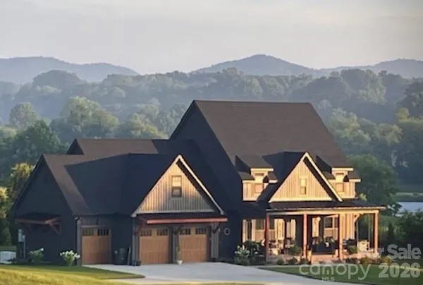 a front view of a house with a yard and mountain view in back