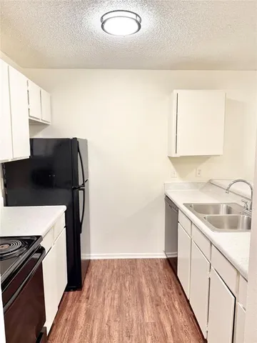 a kitchen with a sink a refrigerator and wooden floor