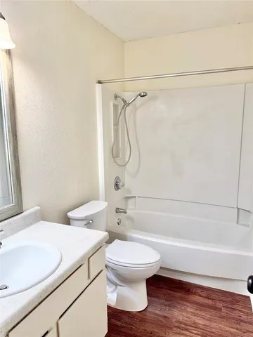 a bathroom with a granite countertop bathtub shower sink vanity and toilet