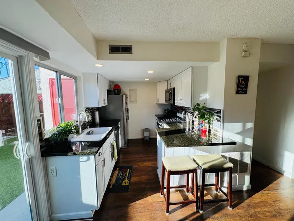 a kitchen with stainless steel appliances kitchen island granite countertop a dining table chairs and a refrigerator