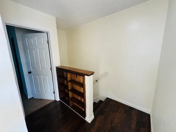 a view of a hallway with wooden floor and a cabinet