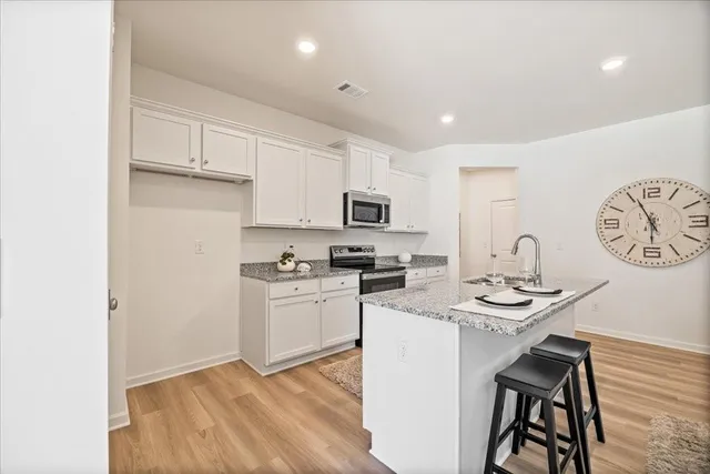 a kitchen with stainless steel appliances granite countertop a stove top oven a sink a dining table and chairs with wooden floor