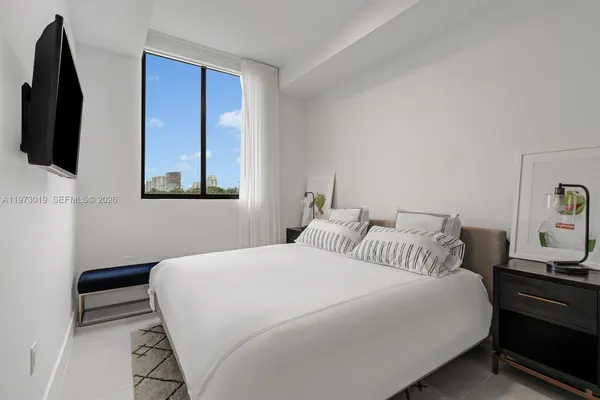 a bedroom with a bed and a flat tv screen on a dresser