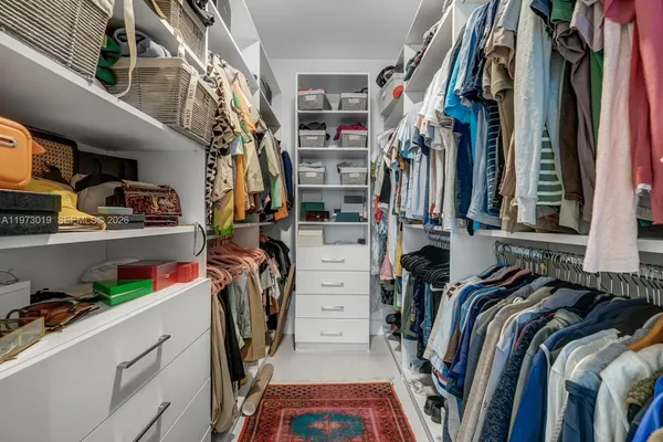 a view of walk in closet with clothes and shoes