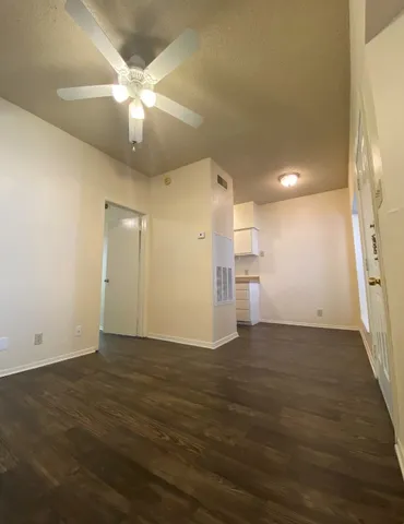 an empty room with wooden floor and ceiling fan