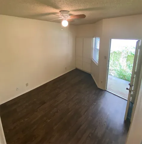 an empty room with wooden floor fan and windows
