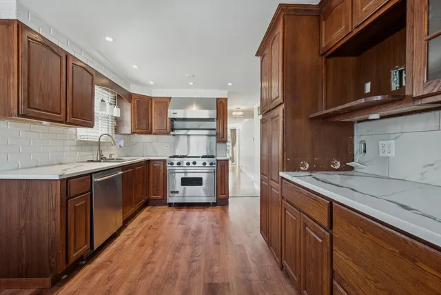 a kitchen with stainless steel appliances granite countertop wooden cabinets a stove top oven a sink and dishwasher