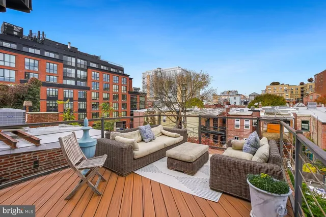 a view of a patio with couches table and chairs with wooden floor and fence