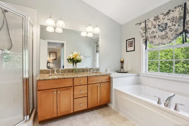 a bathroom with a granite countertop sink a large mirror a bathtub and next to a window