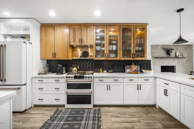 a kitchen with stainless steel appliances kitchen island granite countertop a stove a sink and white cabinets