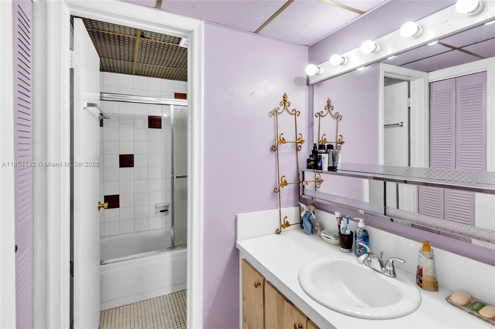 1855 West 62nd Street, Unit E306 Hialeah, FL 33012 - Photo 12 of 35 a bathroom with a sink vanity granite tub and a mirror
