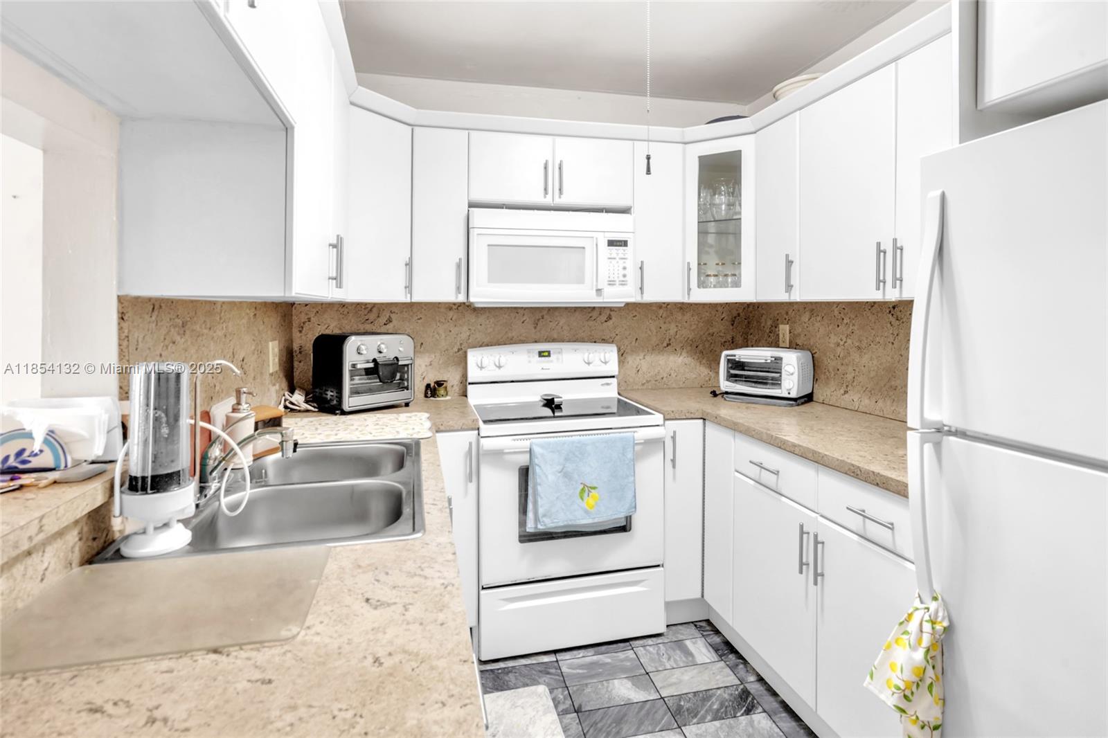 1855 West 62nd Street, Unit E306 Hialeah, FL 33012 - Photo 4 of 35 a kitchen with a sink stove and refrigerator